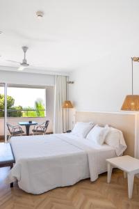 a white bedroom with a large bed and a table at Hotel MC San José in San José