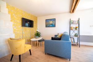 sala de estar con sofá azul y silla amarilla en Le Clos Eugenie - Charmante maison avec jardin et vue sur la Loire, en Gennes