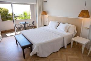 a bedroom with a large white bed and a balcony at Hotel MC San José in San José