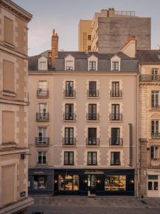 Un grand bâtiment blanc avec de nombreuses fenêtres dans l'établissement Le Nemours - Appartements Parcheminerie, à Rennes