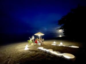 a group of people sitting under an umbrella on a beach at Phi Phi Relax Beach Resort in Phi Phi Islands