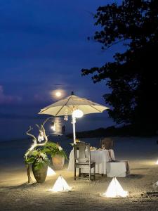 a table with an umbrella on the beach at night at Phi Phi Relax Beach Resort in Phi Phi Islands