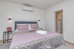 a white bedroom with a large bed with purple sheets at Rooms Nilda in Poreč