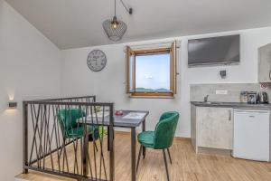 a kitchen with a table and green chairs in a room at Rooms Nilda in Poreč