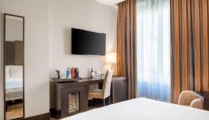 a hotel room with a television and a bed at NH Collection Victoria in Granada