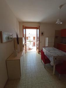 una cucina con tavolo e una stanza con porta di Villetta indipendente in villaggio a 2 passi dal mare a Santa Maria al Bagno