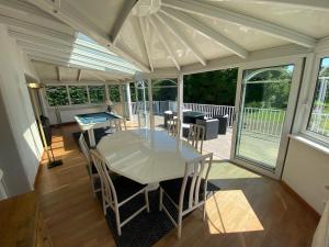 a conservatory with a white table and chairs on a deck at Magnifique villa à 5 minutes de Colmar in Horbourg