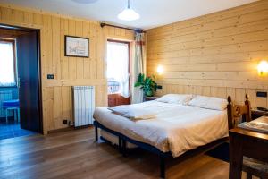 sypialnia z dużym łóżkiem w drewnianej ścianie w obiekcie Santa San w mieście Champoluc
