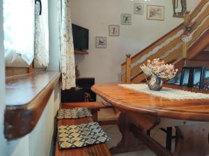 Habitación con mesa de madera y jarrón de flores. en Cottage "Le None"-villa e giardino, en Gonàrs