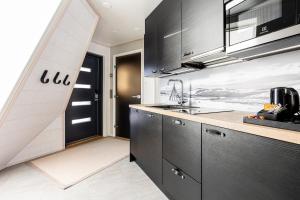 a kitchen with a refrigerator, sink, and cabinets at Glass Resort in Rovaniemi