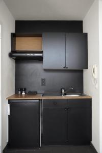 una cocina con armarios negros y fregadero en Edville Studio, en Gante