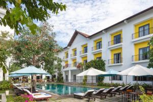 um hotel com piscina, cadeiras e guarda-sóis em ÊMM Hotel Hoi An em Hoi An