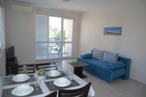 a living room with a table and a blue couch at Divela 3 Apartments in Nesebar