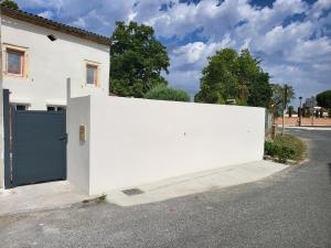 a white house with a blue door on a street at Maison de campagne individuelle et patio in Poulan-Pouzols