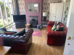 a living room with two leather couches and a fireplace at No.1 The Coach House in Silverdale