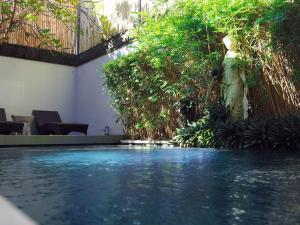 a swimming pool with blue water and plants at Sonti Villa in Seminyak
