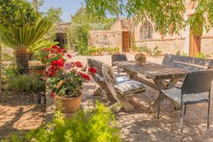 マナコルにあるMurtera- Traditional country manor house for 9 people 5 bedrooms and 4 bathrooms near Sant Llorençの木製のテーブルと椅子、花のある庭園
