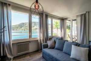 a living room with a blue couch and a large window at La Finestra Blu by Quokka 360 - with a panoramic lake view in Ponte Tresa