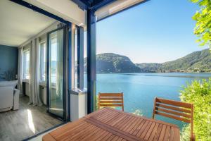 balkon ze stołem i krzesłami oraz widokiem na jezioro w obiekcie La Finestra Blu by Quokka 360 - with a panoramic lake view w mieście Ponte Tresa