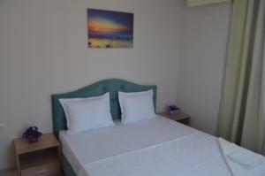 1 cama con almohadas blancas y una foto en la pared en Divela 3 Apartments, en Nesebar