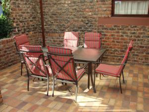 una mesa y cuatro sillas rojas y una pared de ladrillo en Cosy-Corner Guest House, George en George