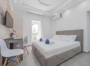 a white bedroom with a bed and a desk and a chair at Casa di Fratelli in Budva