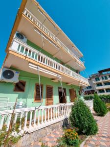 a green house with a white balcony and stairs at Apartment Celaj Velipoje in Velipojë