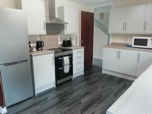 a kitchen with white cabinets and a stove top oven at Carvetii - Zelda House - 4 bedroom house, sleeps 8 in Oakley