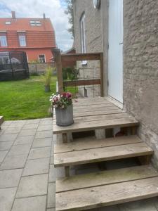 a wooden bench on a porch with a pot of flowers at Lillahuset i Helsingborg! in Helsingborg