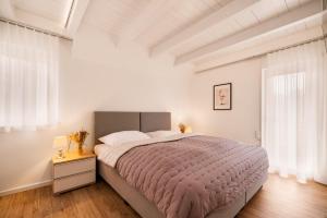 a white bedroom with a large bed and windows at Ferien-Wohlfühlapartment Seekretzer - mit priv Strandzugang in Friedrichshafen +24 photos