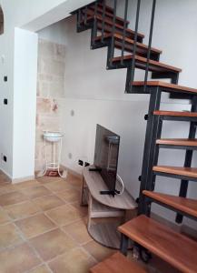een woonkamer met een tv en een trap bij Casa Santa Chiara in Mola di Bari