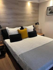 a large bed with yellow and black pillows on it at Au Bec Fin Hôtel in Aix-les-Bains