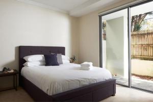 a bedroom with a large bed and a large window at Warrawee Garden - Premium 3 bedroom apartment in Warrawee