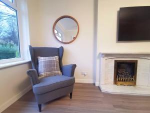 a blue chair in a living room with a fireplace at Cosy 2 Bedroom Family Home In Glasgow City in Glasgow