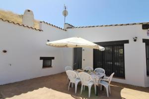 - une table avec des chaises blanches et un parasol sur la terrasse dans l'établissement Casa Cueva Bella Vista, à Alcudia de Guadix