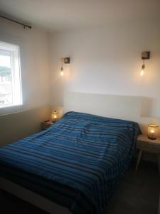 ein Schlafzimmer mit einem Bett mit einer blau gestreiften Decke in der Unterkunft Appartement contemporain le Vendome à 90m de la plage in Le Grau-du-Roi