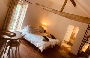 a bedroom with a bed and a table and a window at Studio la Grange in Fontevraud-l'Abbaye