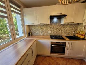 a kitchen with white cabinets and a stove top oven at Apartament 5 minut spacerem od plaży in Giżycko