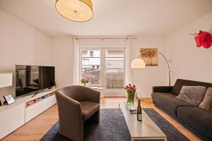 ein Wohnzimmer mit einem Sofa und einem TV in der Unterkunft Wohlfühl-Apartment Auenwald im Naturschutzgebiet mit Privatstrand in Friedrichshafen