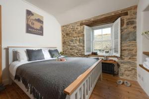 a bedroom with a bed and a stone wall at Eastleigh Cottage, Marazion in Marazion