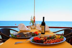 a table with two plates of food and a bottle of wine at Apartments Hidri in Ulcinj
