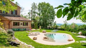 un patio trasero con piscina y una casa en CASA MELOGRANO 11&2, Emma Villas, en Montefelcino