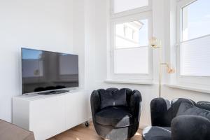 uma sala de estar com 2 cadeiras e uma televisão de ecrã plano em JOHOUSE Apartment 7 em Warnemünde
