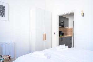 Duas camas brancas num quarto com uma cozinha em JOHOUSE Apartment 7 em Warnemünde