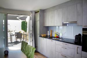 a kitchen with white cabinets and a table with green chairs at Ferienwohnung Grünegg in Gersau