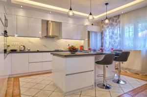 a kitchen with white cabinets and a island with bar stools at Noufris House Roda Corfu in Roda