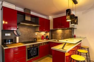 a kitchen with red cabinets and yellow bar stools at 15 Rhône beau T2 avec parking gratuit in Annecy