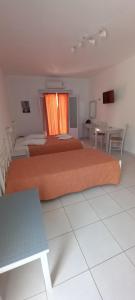 a bedroom with two beds and a table and a window at Hotel Agnadi in Amorgos