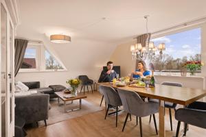 a man and woman sitting at a table in a living room at Ferien-Apartment Eisvogel im Naturschutzgebiet mit Privatstrand in Friedrichshafen