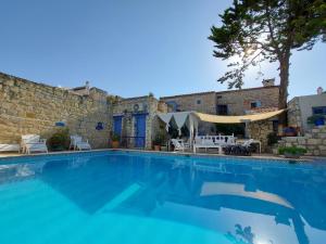 a swimming pool in front of a stone wall with a house at 1882 Hotel in Alaçatı